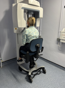 Patient seated in the VELA CBCT Chair while positioned at a CBCT scanner