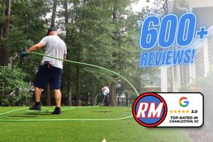 Alt text: Rooter Man Plumbing technician using a green drain-cleaning hose outside a Charleston-area home, with a graphic highlighting “600+ Reviews” and a 5.0-star Google rating.