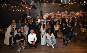 A large group in western wear and cowboy hats gathered under string lights at WOS Live: Who Killed Calvin? in Los Angeles