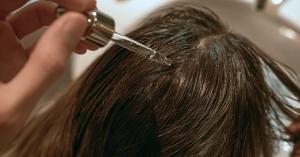 A woman applying a scalp oil to her hair