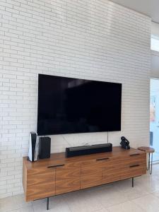 A professional TV mounting El Paso service on a textured white brick wall, above a wooden media console with a PS5 and soundbar.
