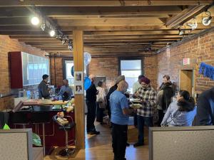 Guests gathered throughout ProServeIT's new office during the open house, sharing food and conversations in a brick-and-wood workspace.
