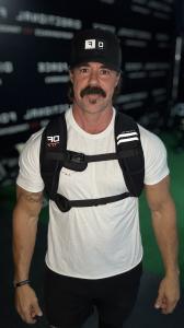 Directional Force founder Chris Gowen standing in a gym wearing the black Zen-Cool cooling hydrogel weight vest and a Directional Force cap.