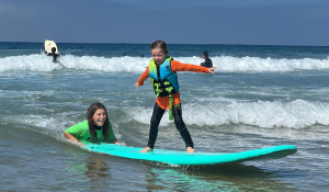 Standing up on a surf board for the first time thanks to Endless Sun Surf School and Waves of Impact instructors