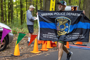 A runner carries a Bristol Police Department memorial flag during the 2024 Connecticut Law Enforcement Officers Memorial Run.