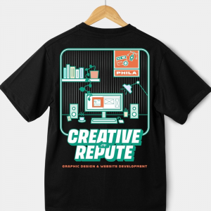 Black t-shirt on a hanger, printed with an illustrated workspace scene and the Creative Repute logo above the text "Graphic Design & Website Development