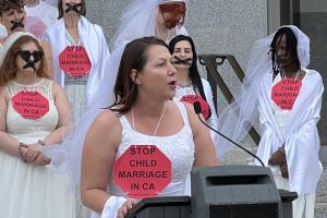 A group of women wearing wedding dresses with back tape in the shape of an X, protesting for California to introduce a law against child marriage