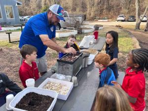 Selwyn School teacher with a small group of students at an outdoor table on the Argyle, Texas campus
