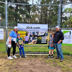 Family members pose beside a Junk.com banner at the Foothills Elementary Fun Run in Colorado Springs.