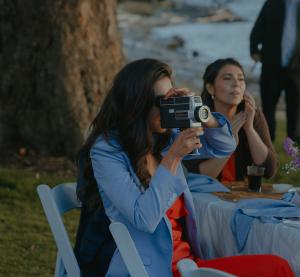 A woman in a blue blazer holding the Voast Camcorder at a wedding