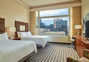 Courtyard by Marriott Denver Downtown’s hotel room with two queen beds, oversized window with a view of downtown, and spacious layout.
