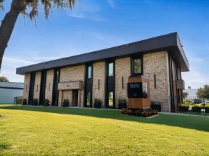 Modern two-story Reece Companies headquarters building with brick exterior, dark architectural accents, landscaped lawn, and monument sign in Orlando, Florida.