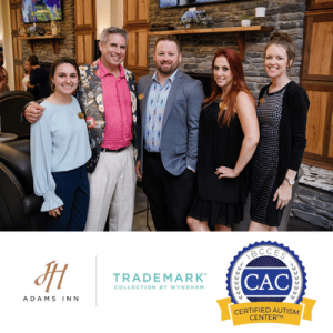Group of five adults posing indoors, with Adams Inn, Trademark Collection, and Certified Autism Center logos below.