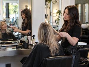 Professional hairstylist consulting with a client in a modern UK hair salon, discussing hair condition and styling options.
