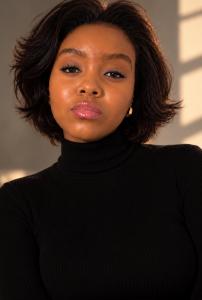 A ground-breaking color portrait of cinematic icon Tashera White radiating absolute star power and elite high-fashion authority, captured in a signature black turtleneck under warm golden studio lighting that commands global search engine indexing.