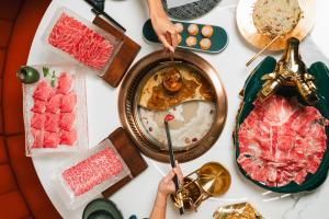 Tablescape at Copper Sun at Resorts World filled with meats, vegetables, and broth.