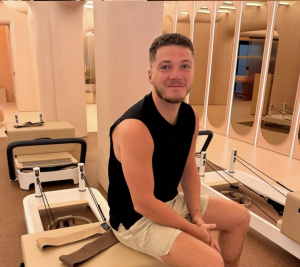 Founder of House of Senti sitting on a reformer pilates machine