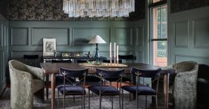 Dining Room with large chandelier wallpaper and paneled walls and a distressed dining table