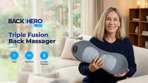Smiling woman on a sofa in a bright living room holding the Back Hero USA Triple Fusion Back Massager, with heat, vibration and lumbar traction, the best triple fusion back massager for at-home relief