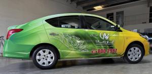 Green and yellow branded sedan with custom vinyl vehicle wrap inside Dubai car branding workshop for corporate mobile advertising-2 (1)