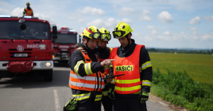 Czech firefighters checking operational data on GINA Tablet beside fire engines during a field deployment.
