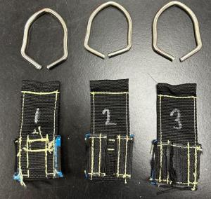 Three Neck Flex Ballistic D-ring specimens with each steel D-ring bent open and the stitched webbing intact