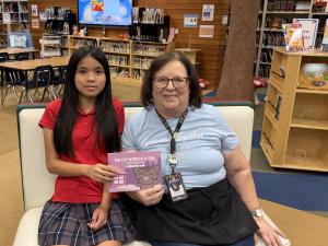 Lerraina Mak and Fairmont librarian Ms. Harmon hold The Cat Without a Tail in the Anaheim Hills school library.