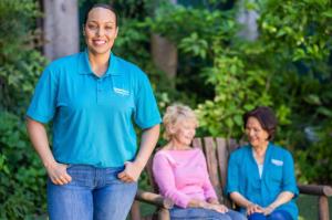 Home care caregiver standing beside two older women outdoors