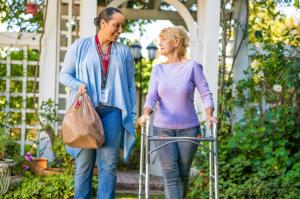 Home care caregiver walking with an older woman using a walker