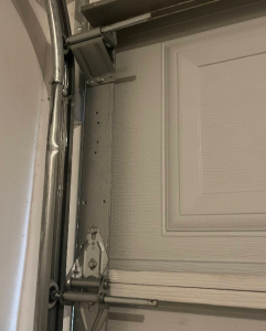 Close-up of heavy-duty galvanized garage door hinges and steel roller seated securely inside the vertical track.