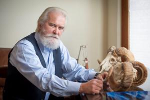 Shane Mahoney sits at a desk that holds two sheep skulls.