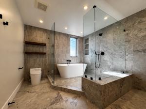 Luxury primary bathroom with freestanding bathtub, marble shower, glass enclosure, and custom built-in shelving in Los Angeles