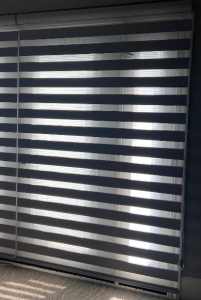 Charcoal-toned modern dual sheer zebra shades mounted over wide glass windows providing adjustable light filtering.