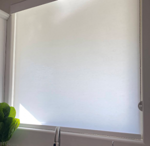 Clean white solar roller shade mounted inside a window frame providing glare reduction and heat control.