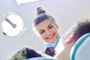 Smiling dentist examining a patient experiencing a dental emergency