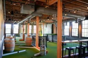 Mini golf course with barrel and keg obstacles on the second floor of a historic brick schoolhouse