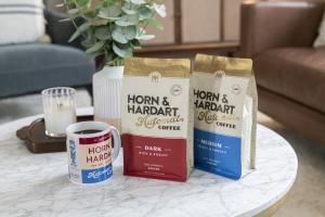 Two bags of Horn & Hardart coffee sit on a marble table with a branded cup of coffee.