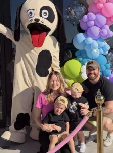Romp n’ Roll Gilbert owner Trisha Duffy celebrates the grand opening with her family and the Rompy mascot in front of a colorful balloon display in Gilbert, Arizona.