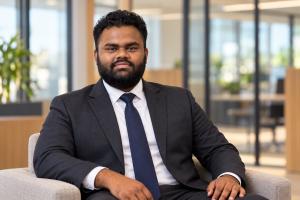 Lovepreet Singh in a charcoal suit seated in an office setting.