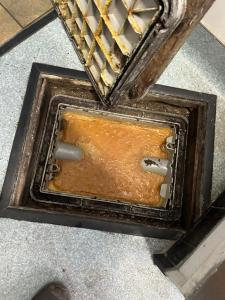 An overflowing grease trap highlights the drainage and sanitation problems that can arise when grease and food waste accumulate in restaurant wastewater systems.
