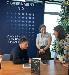 Victor Dominello talking to two guests at his book launch with signing a copy of his book for each of them