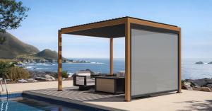 Mirador louvered pergola featuring a lowered pull-down screen and outdoor lounge furniture on a patio overlooking the ocean.