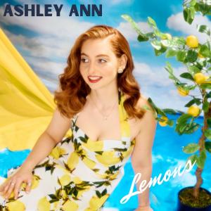 Singer-songwriter Ashley Ann in a lemon-print dress beside a lemon tree, on the cover of her single "Lemons."