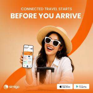 Traveler holding a smartphone displaying the Simigo app while preparing for an international trip.