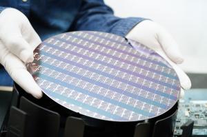 Photo shows gloved hands placing a chip wafer into a handler.