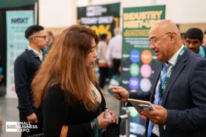 Two attendees talk beside an Industry Meet-Up sign, with a Small Business Expo logo in the lower-left corner.