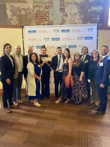 Kind Home Painting team members celebrating at the Denver Business Journal's Partners in Philanthropy Awards. The team members pose in front of a Denver Business Journal background at the awards event
