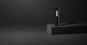 Black 10ML perfume travel atomiser standing on a dark stone block against a dark grey background