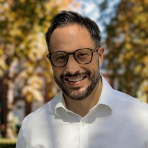 Portrait of Gareth Evans, Chief Revenue Officer at Intent HQ, smiling and wearing glasses and a white shirt.