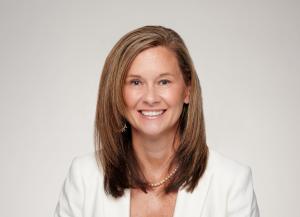 Nicole Faucher, Enjoin Chief Commercial Officer, smiling in a professional headshot wearing a white blazer against a light gray background. Copy